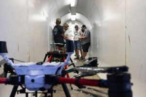 Attendees look at drones used to haze waterfowl while taking cover from hail in the tunnel leading to the Berkeley Pit viewing stand during a presentation at the Berkeley Pit in Butte on July 16. Photo Credit: Megan Nielsen, Montana Standard